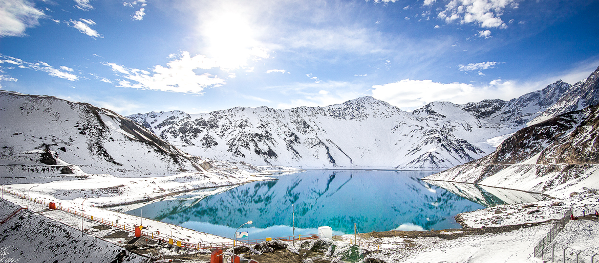 Paisagem de inverno no Embalse El Yeso, com neve cobrindo as montanhas e águas cristalinas cercadas por gelo